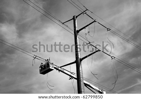 Horizontal black and white photo of electric transmission line being constructed