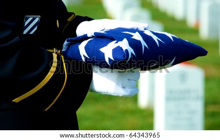 Honor Guard holding folded American flag at grave site at Arlington National Cemetery