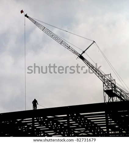 Dramatic Silhouette of Steel Worker and Crane at Construction Site