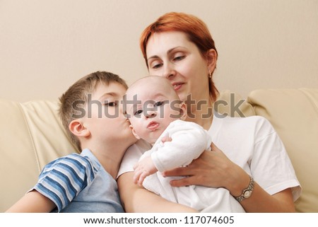 Happy mother with two children. Boy kisses the younger brother.