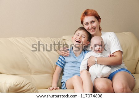 Happy mother with two children sits on a sofa.