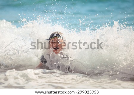 The boy swiming in sea waves on a beach