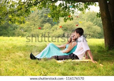 young couple sitting under a tree hugging