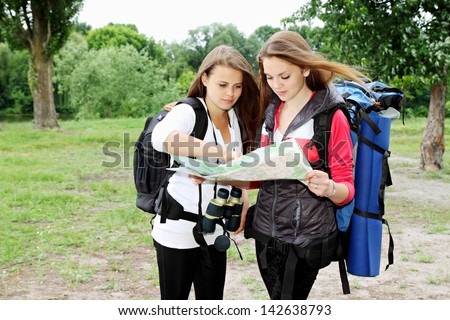 Two young girls with backpacks view map
