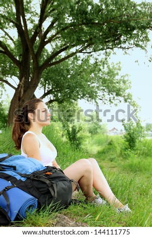 woman with a backpack resting on the bank of the river