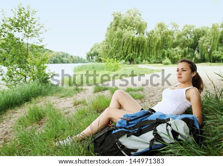 woman with a backpack resting on the bank of the river