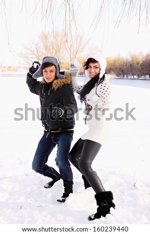 happy couple throwing snowballs in the park