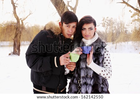 Young couple with a hot drink in winter outdoors