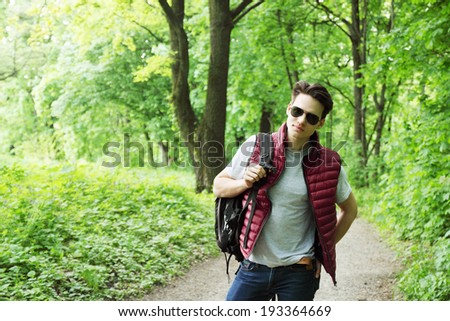young man with a backpack walks in the forest