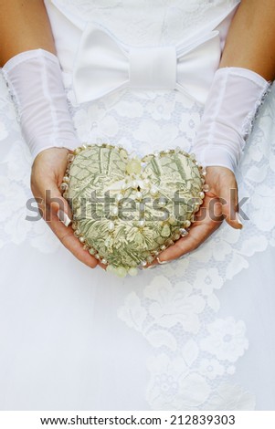 Bride is holding a vintage heart decorated with pearls