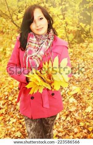 Woman with the autumnal leafs in the pink coat