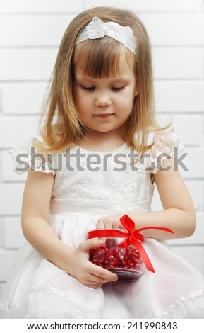 little girl holding a jar of pomegranate berries