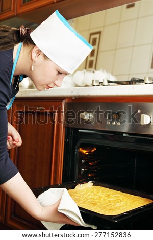 woman pulls out of the oven cake