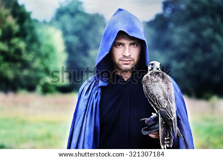 handsome young man in a raincoat with a falcon in his hand