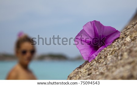 Close up of flower laying on a granite bolder and a young woman, or tourist in the Similan Islands, Andaman Sea, Thailand.
