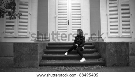 White shoes. Girl or Woman sitting on stairs. Black and white concept of someone waiting, thinking, taking a time out, or day dreaming,