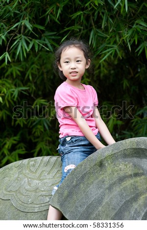 cute little asian girl sit on Stone elephant