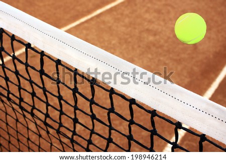 Tennis  ball and net on a clay court.
