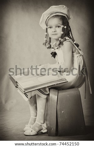 Adorable african girl browsing an family album.  Vintage style