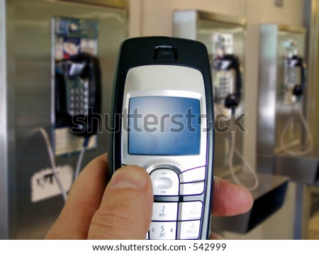Close-up of cell phone held by man in front of bank of public old-style phones.
