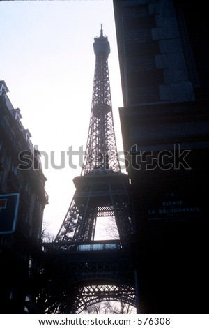 Eiffel Tower looms up Paris avenue in silhouette against the cold winter sky.