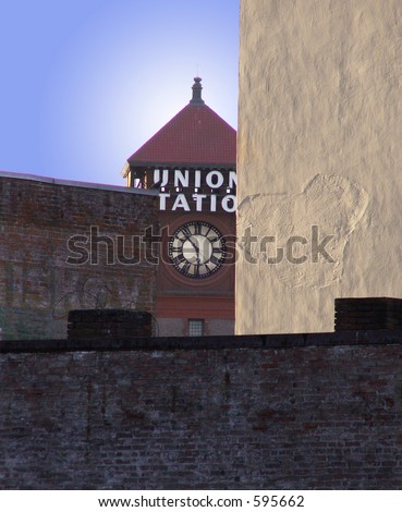 Clock tower of union station seen sandwiched between buildings in this intriguing city scene.