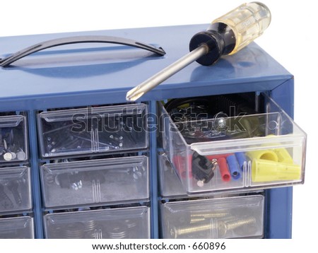 Screwdriver rests on top of hardware organizer box with one drawer open -- isolated on white background.
