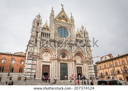 SIENA, ITALY - JULY 11, 2013: Tourists stroll around 13th century Siena Cathedral in a center of Siena, Italy. The Cathedral is a marble church dedicated to Holy Mary, Our Lady of the Assumption.