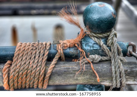 wooden post attached to a railing in the city of Amsterdam by different colored ropes.