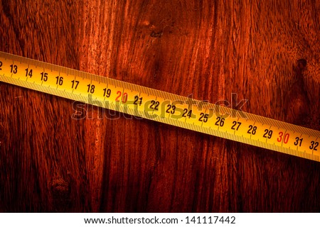 Yellow measure tape on solid wood