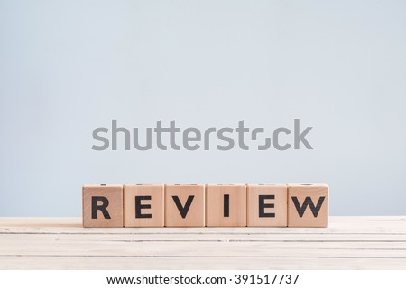 Review headline sign made of wood on a table