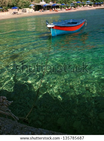 Blue lifeboat. The old wooden blue boat is attached, moored by a rope to a stone pier. Blue transparent sea, summer, sea, beach. Greece. Gulf of Corinth, Lutraki.