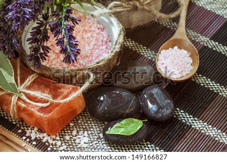 Natural soap, spa stones in water drops, sea salt and lavender flowers lying on a bamboo mat