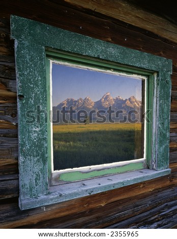 The Teton Mountain Range reflecting in the window of a ranch house, located in Grand Teton National Park, Wyoming.