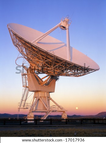 A Radio Telescope, part of the Very Large Array (VLA), in New Mexico with the full moon.