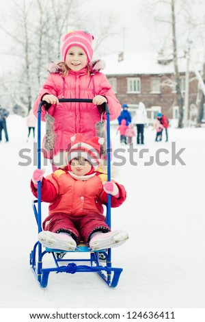 Happy kids skating and sledding in winter outdoors