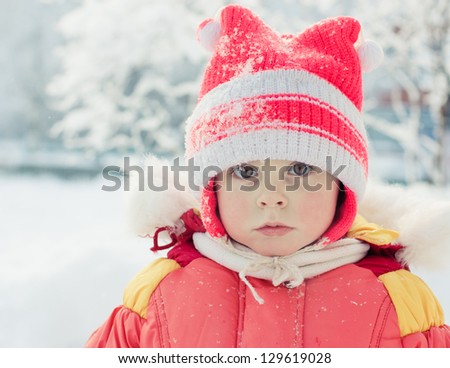 The kid in the red jacket under snowfall in the winter.