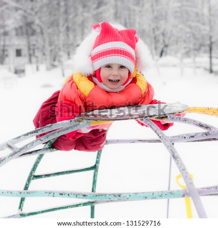 Beautiful happy kid in the red warm clothing in the winter outdoors.