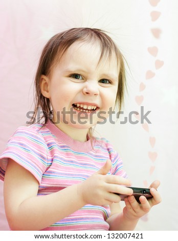 Baby with mobil telephone on a pink background.