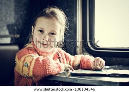The girl sitting at a desk writing in train.