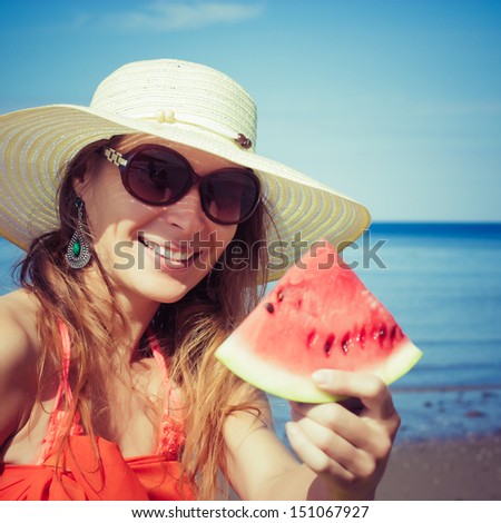 Young stylish lady in a hat and sunglasses at sea with watermelon
