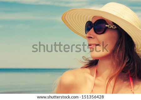Relaxing beach woman enjoying the summer sun happy in a wide sun hat and sunglasses at the beach