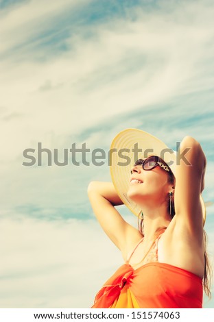 Relaxing beach woman enjoying the summer sun happy in a wide sun hat at the beach with face raised to the sunlight.