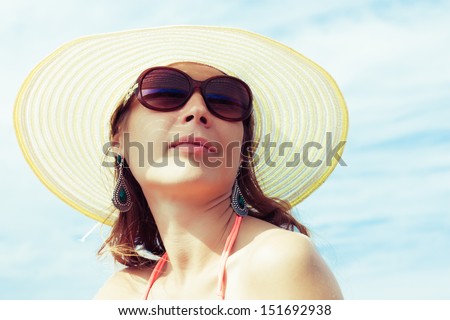 Relaxing beach woman enjoying the summer sun happy in a wide sun hat and sunglasses at the beach