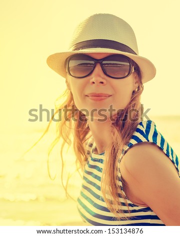 Relaxing beach woman enjoying the summer sun happy in a cap and sunglasses