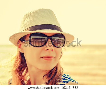 Relaxing beach woman enjoying the summer sun happy in a cap and sunglasses