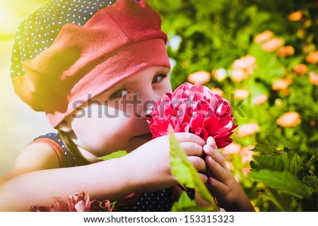 Portrait of a three year old little girl outdoor in a flower garden smelling the flowers.