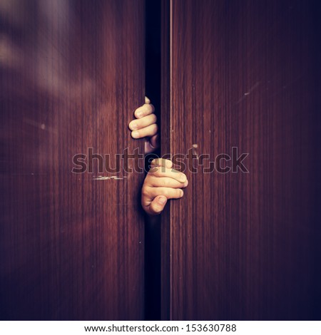 A child hides in the closet, closing the door.