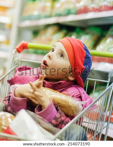 Little girl in a big store with products in the cart.