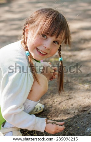 Little girl playing at sand painting stick.